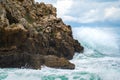 Ocean water splash on rock beach with beautiful sky and clouds. Sea wave splashing on stone at sea shore on winter. Sea waves lash Royalty Free Stock Photo