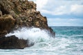 Ocean water splash on rock beach with beautiful sky and clouds. Sea wave splashing on stone at sea shore on winter. Sea waves lash Royalty Free Stock Photo