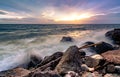 Ocean water splash on rock beach with beautiful sunset sky and clouds. Sea wave splashing on stone at sea shore on summer. Nature Royalty Free Stock Photo