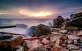 Ocean water splash on rock beach with beautiful sunset sky and clouds. Sea wave splashing on stone at sea shore on summer. Nature Royalty Free Stock Photo