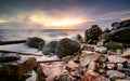 Ocean water splash on rock beach with beautiful sunset sky and clouds. Sea wave splashing on stone at sea shore on summer. Nature Royalty Free Stock Photo