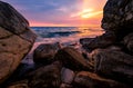 Ocean water splash on rock beach with pink and golden sunset sky. Sea wave splashing on stone at sea shore on summer. Tires and Royalty Free Stock Photo