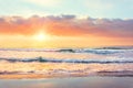 Ocean wave on the beach at sunset time, sun rays