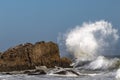 Ocean wave breaking on rock, spray curling in the air. Ocean, wave, large rock in surroundings. Blue sky. Royalty Free Stock Photo