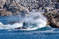 Ocean wave crashing against rocks on a bright sunny day Royalty Free Stock Photo