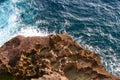 An ocean wave crashing against a textured rock at sunset Royalty Free Stock Photo