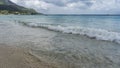 An ocean wave rolls onto a sandy beach and foams. Royalty Free Stock Photo