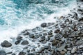 Ocean waves on black pebble stone coast