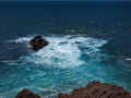 Ocean waves breaking on the rocky coast of hardened lava. Surf on the water around the stone. Lanzarote