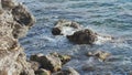 Ocean waves breaking with splashes on wet rocks on beach.