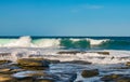 Ocean waves crash against eons old volcanic rock and water runs and breaks the stone - with tiny boats on the horizon Royalty Free Stock Photo