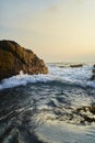 Ocean waves crash against rocks at sunrise. Seascape with splashing water near coastline. Marine natural beauty. Serene