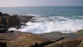 Ocean waves crash onto rocky coastline. Seascape with natural rhythms, spray rises. Coastal boulders meet surf, creating