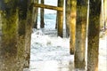 The ocean waves crash into the pilings of the beach fishing pier underbelly