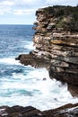 Ocean Waves Crashing Onto Jagged Rock Cliff Face