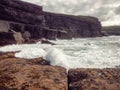 Ocean waves crushing on rough stone coast of rugged Irish coast line with cliffs. Kilkee area, Ireland. Popular travel and tourism Royalty Free Stock Photo