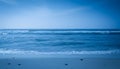 Ocean Waves Gently Rolling Onto Sandy Beach Under A Clear Blue Sky Royalty Free Stock Photo