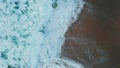 Ocean waves meeting beach making foam aerial view. Sea water crashing seashore