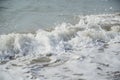 Ocean waves splashing onto the shore of a sandy beach causing white foam and bubbles
