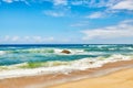 Ocean waves, turbulent sea and rough tides from strong winds crashing onto a boulder at the beach shore with a cloudy