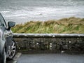 Ocean weaves in focus, Small black car out of focus in foreground. Rosses point, county Sligo, Ireland. Concept travel Royalty Free Stock Photo