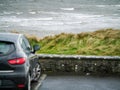 Ocean weaves in focus, Small black car out of focus in foreground. Rosses point, county Sligo, Ireland. Royalty Free Stock Photo