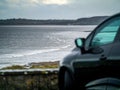 Ocean weaves in focus, Small black car out of focus in foreground. Rosses point, county Sligo, Ireland. Concept travel Royalty Free Stock Photo