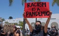 Oceanside, CA / USA - June 7, 2020: Young woman holds a sign saying `Racism is a Pandemic` during Black Lives Matter prote Royalty Free Stock Photo