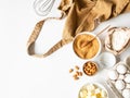 Ocher apron and various baking ingredients - flour, eggs, sugar, butter, nuts on white background. Top view Royalty Free Stock Photo