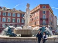 Couple strolls in front of the Fontaine de Soleil, Nice, Italy