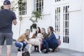 Four pretty girls kneel to Pet a fluffy white dogs while laughing up a the dogs owner standing talking to them