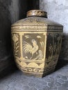 Octagon-shaped glazed water jar with rooster pattern.