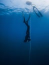 October 03, 2022. Amed, Indonesia. Men in wetsuit with fins training dive in blue ocean. Professional freediving underwater in