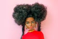 african american Barbie doll with black hair in a red suit standing isolated on a pink background