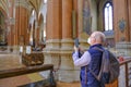 October 2021 Bologna, Italy: Elder man wearing medical face mask and making photo whth a smartphone in the basilica di San Petroni Royalty Free Stock Photo