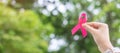 October Breast Cancer Awareness month, adult Woman  hand holding Pink Ribbon with green background for supporting people living Royalty Free Stock Photo