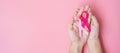 October Breast Cancer Awareness month, adult Woman hand holding Pink Ribbon on pink background for supporting people living and