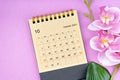 The October 2023 calendar desk and pink orchid on pink background