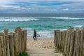 Surfer with a board passing in front of a narrow street with the sea at its end. Campeche Beach Praia do Campeche, in