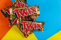 A close-up of Twix cookie bars candy bars on orange blue and yellow background