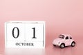 October 01st. Day 1 of month. Calendar cube on modern pink background with car