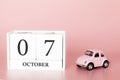 October 07th. Day 7 of month. Calendar cube on modern pink background with car