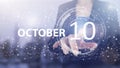October 10th. Day 10 of month, Calendar date. Hand click luminous hologram calendar date on light blue town background. Autumn