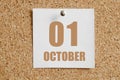 october 01. 01th day of the month, calendar date.White calendar sheet attached to brown cork board.Autumn month, day of