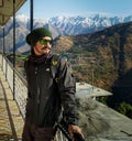 Ready solo traveler with backpack, gazing from homestay balcony at snow-capped Mussoorie mountains, Uttarakhand, India