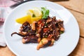 Octopus salad with lemon herbs and spices on white plate / Tentacles squid grilled appetizer food hot and spicy chilli sauce