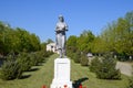 Statue of a collective farmer on a pedestal. The legacy of the Soviet era. A flower bed with tulips and young trees in