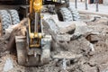 ocus on gravel and dirt going out of the showel of a mechanical digger excavator working in construction site of street renovation