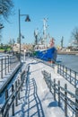 Od blue small fishing boat in a frozen harbor canal.