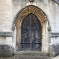 Od church door with wrought iron detail and faces carved in stone Royalty Free Stock Photo